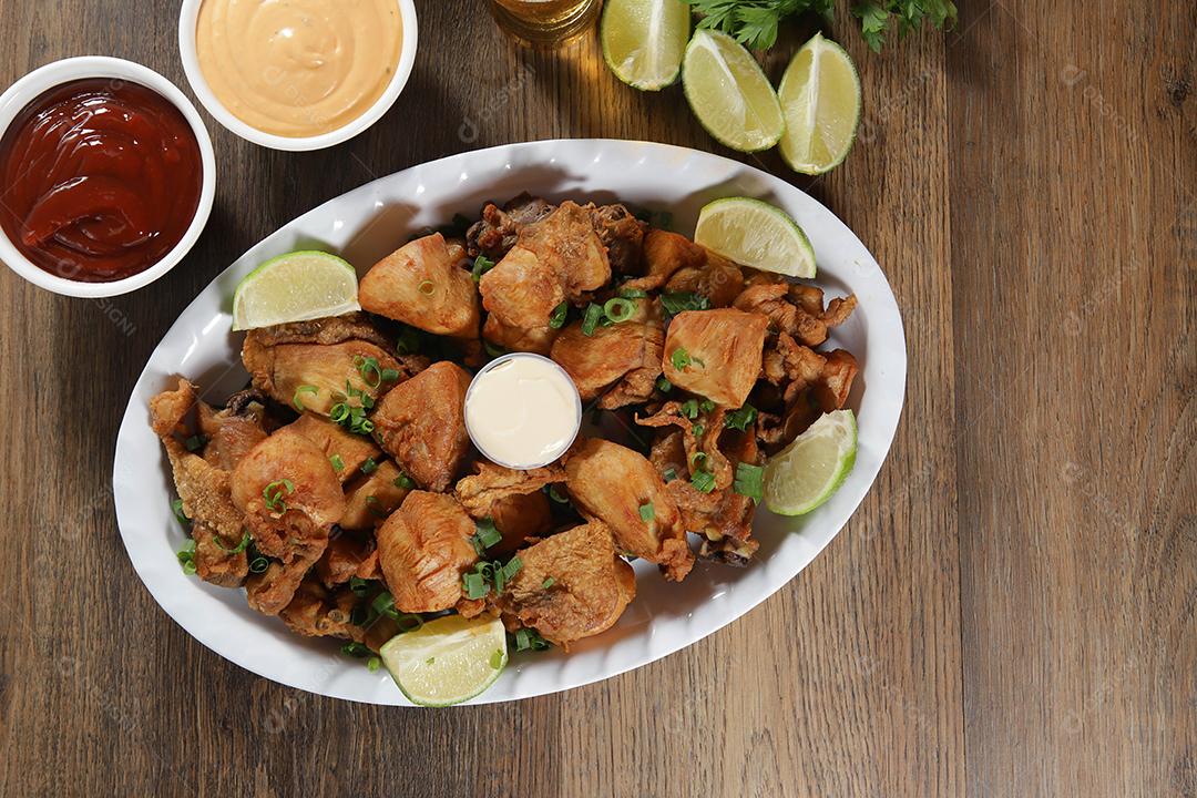 Porção de frango frito com limão. Alface, cebolinha, ketchup e maionese.