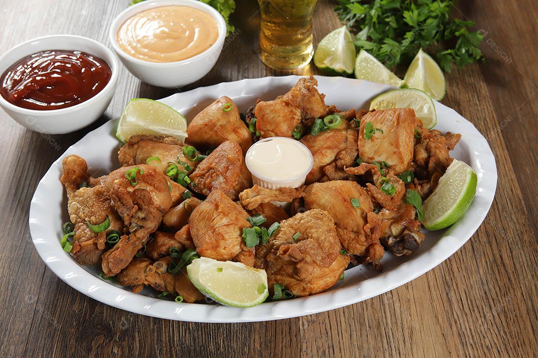 Porção de frango frito com limão. Alface, cebolinha, ketchup e maionese.