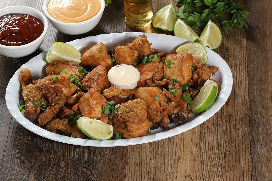 Porção de frango frito com limão. Alface, cebolinha, ketchup e maionese.