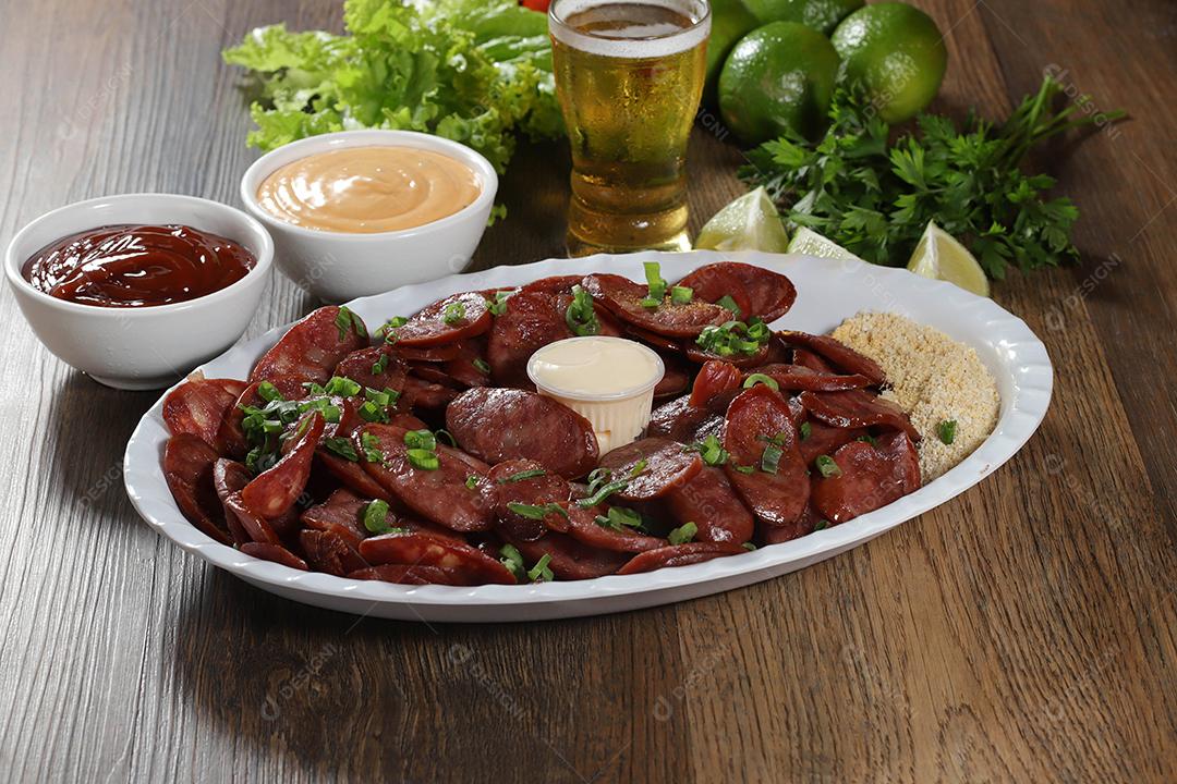 Porção de linguiça calabresa com limão. Alface, cebolinha, ketchup e maionese.