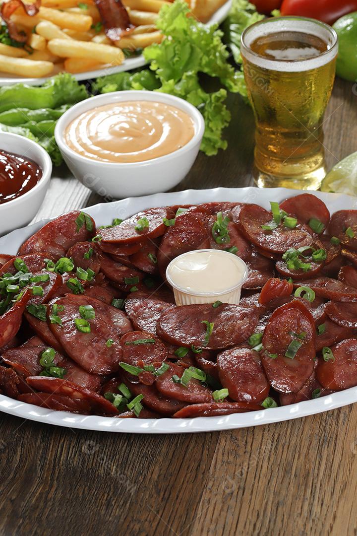 Porção de linguiça calabresa com limão. Alface, cebolinha, ketchup e maionese.