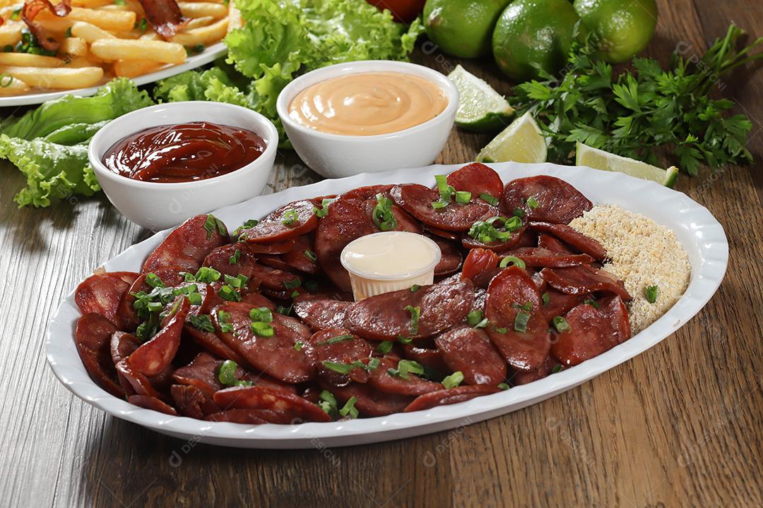 Porção de linguiça calabresa com limão. Alface, cebolinha, ketchup e maionese.