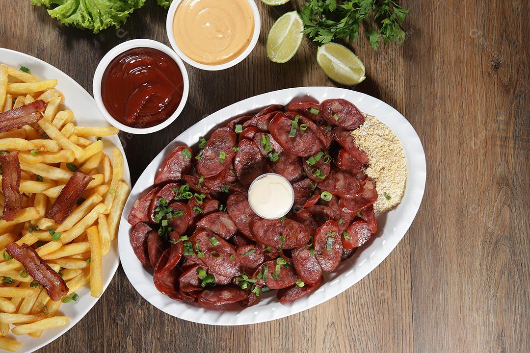 Porção de linguiça calabresa com limão. Alface, cebolinha, ketchup e maionese.