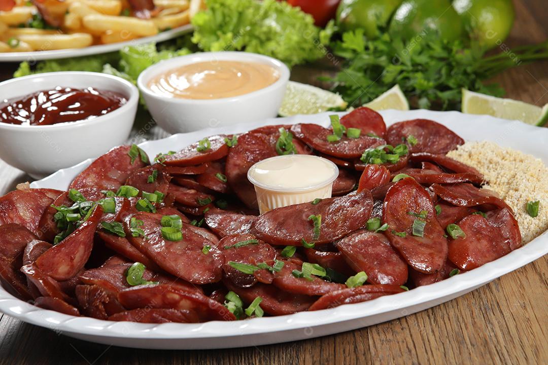 Porção de linguiça calabresa com limão. Alface, cebolinha, ketchup e maionese.