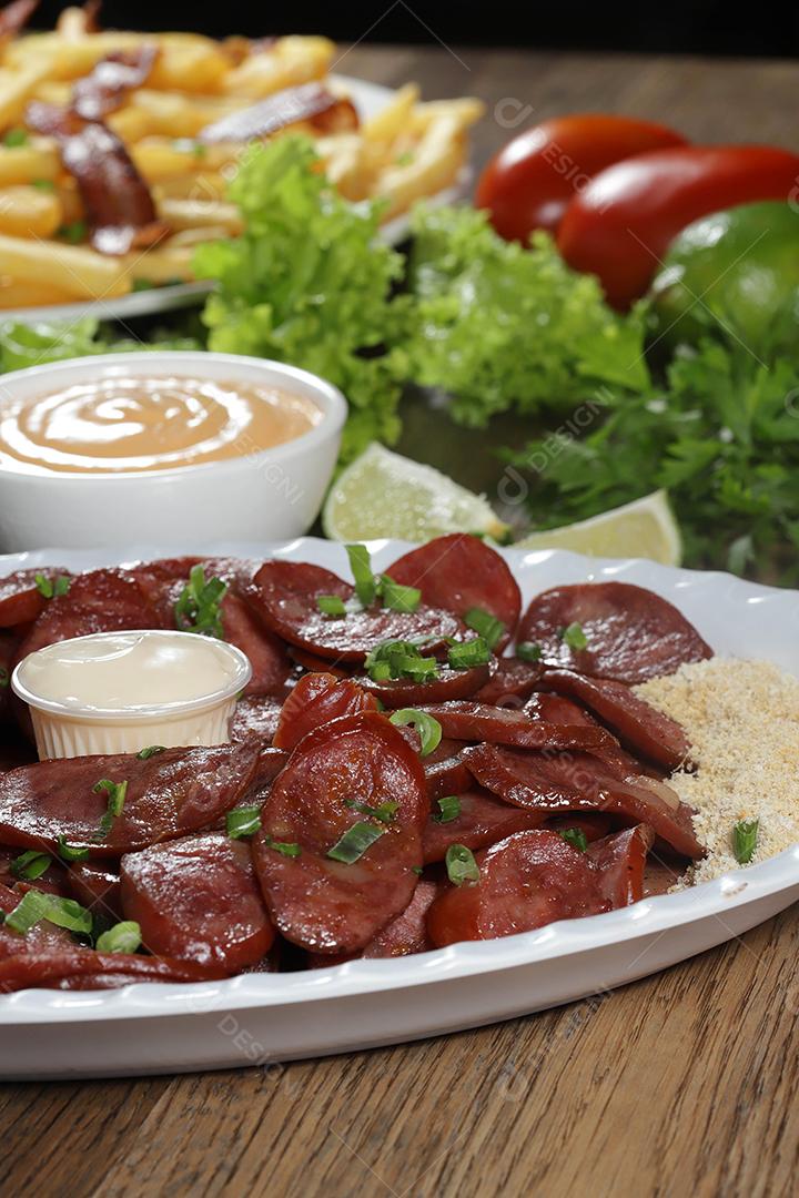 Porção de linguiça calabresa com limão. Alface, cebolinha, ketchup e maionese.