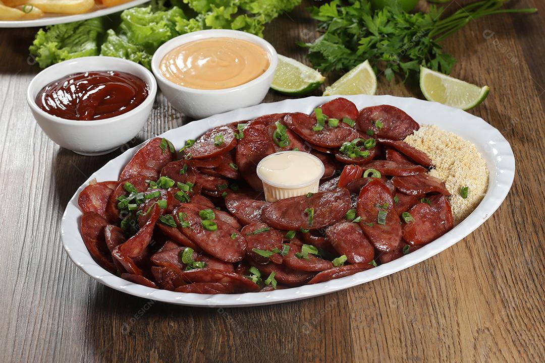 Porção de linguiça calabresa com limão. Alface, cebolinha, ketchup e maionese.