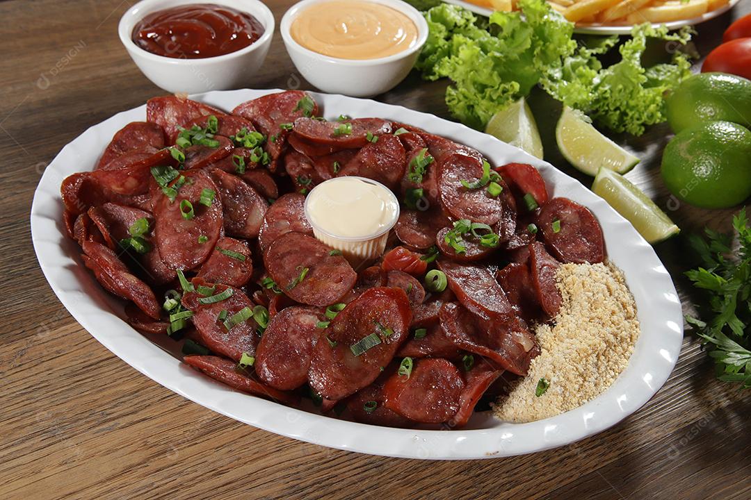 Porção de linguiça calabresa com limão. Alface, cebolinha, ketchup e maionese.