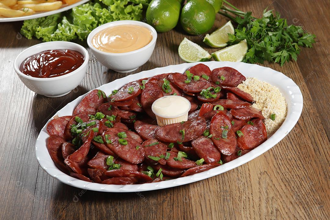 Porção de linguiça calabresa com limão. Alface, cebolinha, ketchup e maionese.