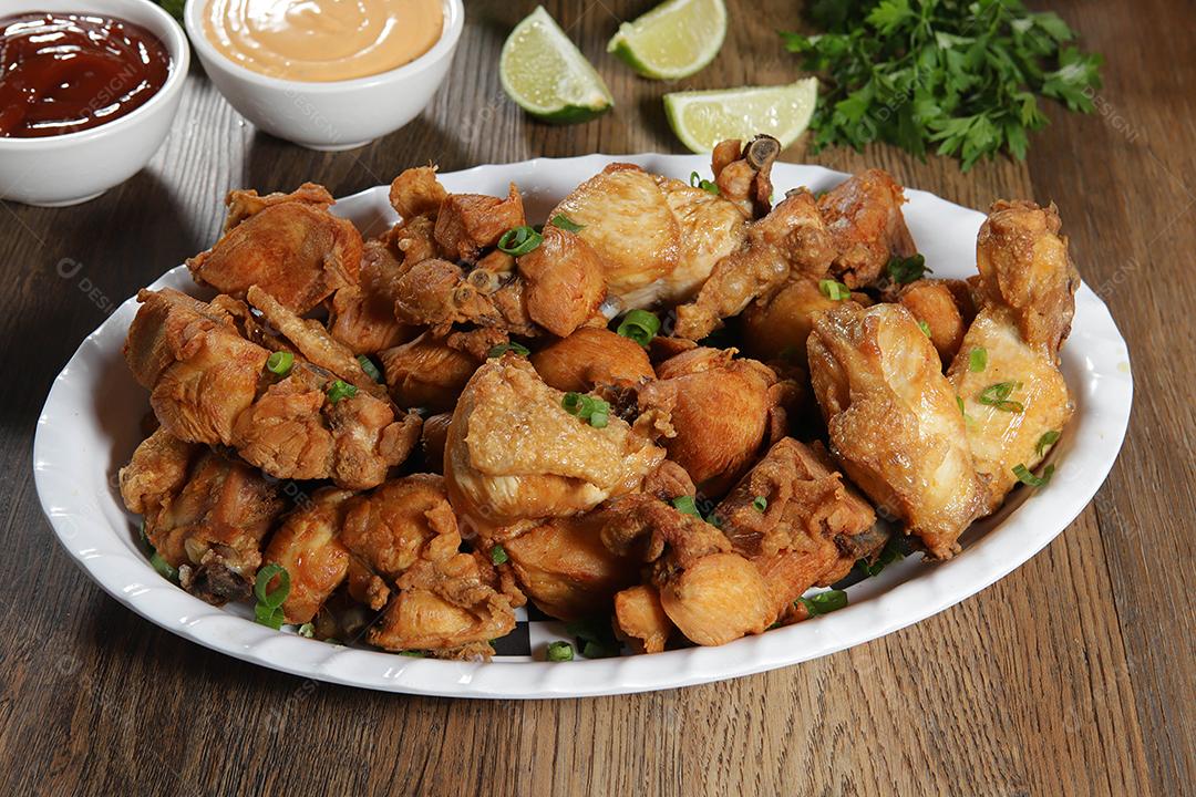 Porção de frango frito com limão. Alface, cebolinha, ketchup e maionese.