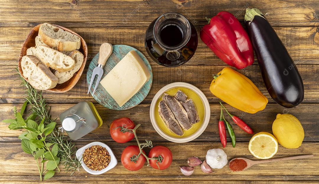 Legumes, azeite, pão, queijo, peixe e vinho e legumes sobre a mesa de madeira. Comida mediterrânea.