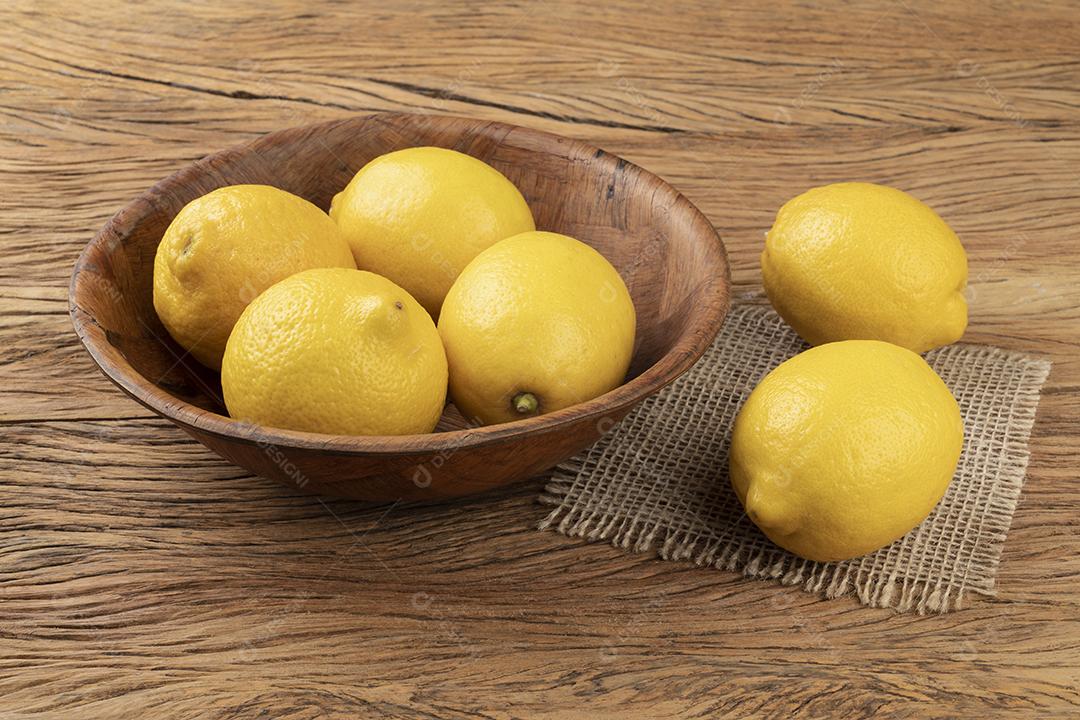 Limões sicilianos em uma tigela sobre a mesa de madeira.
