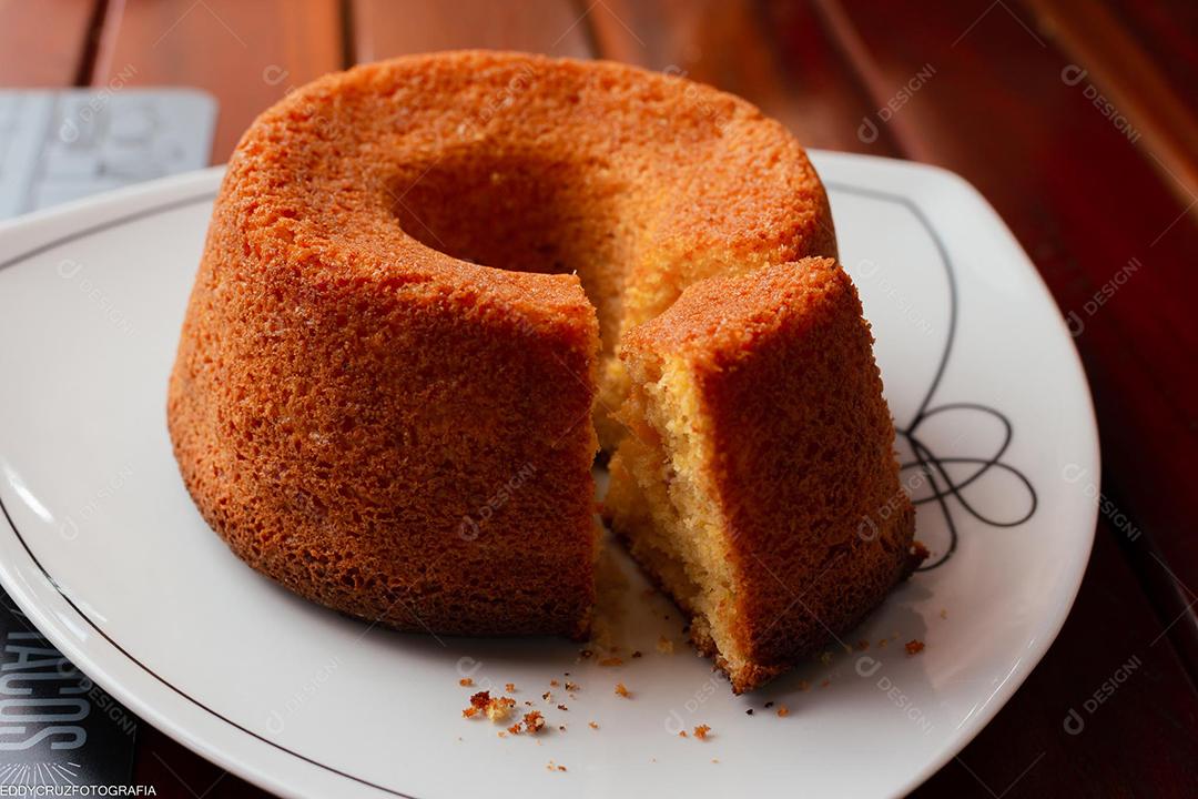 Bolo de milho tradicional brasileiro sobre prato em mesa de madeira.