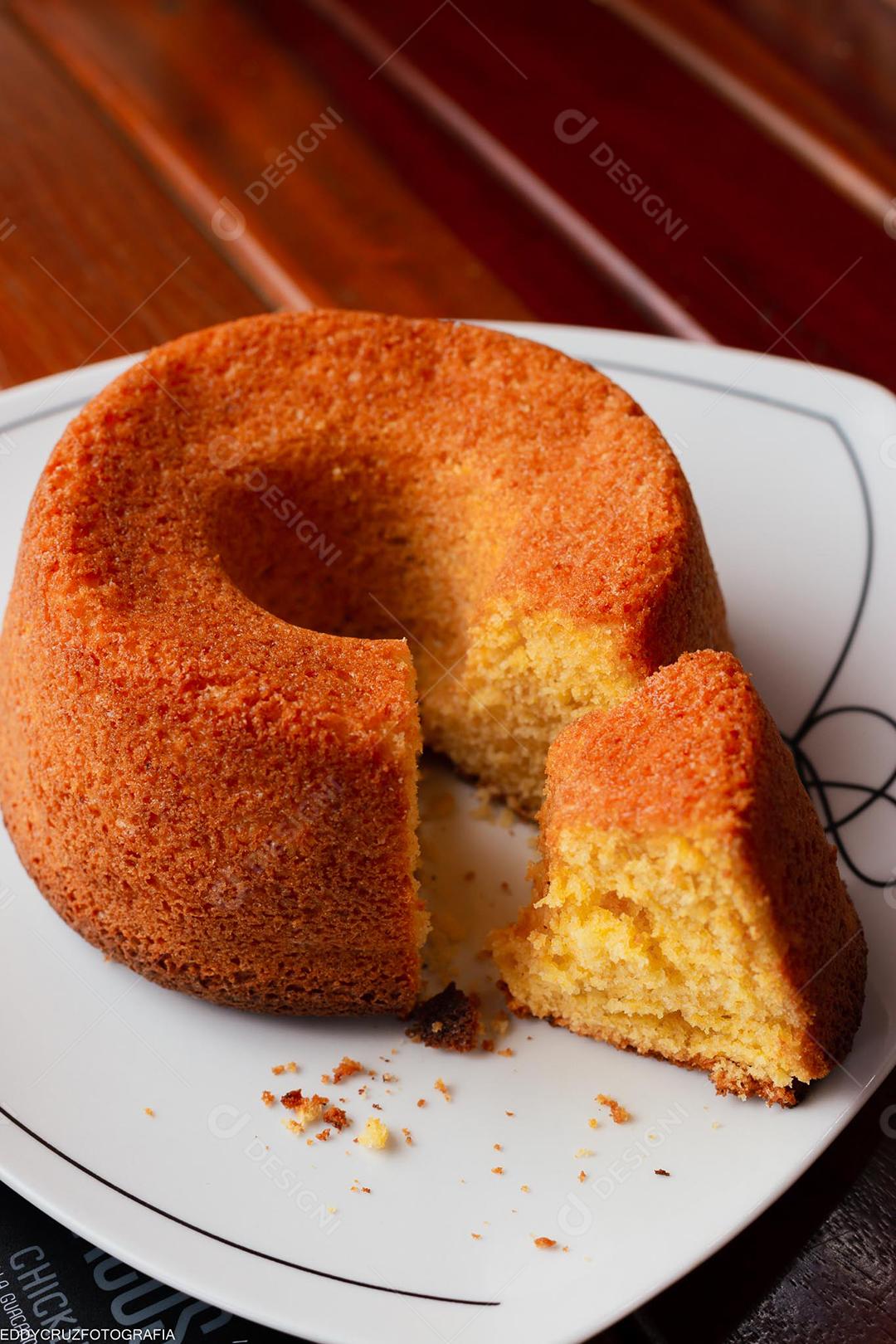 Bolo de milho tradicional brasileiro sobre prato em mesa de madeira.