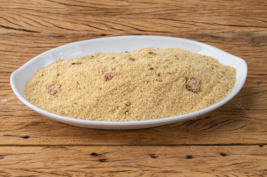 Farofa, acompanhamento típico de farinha de mandioca brasileira sobre mesa de madeira.