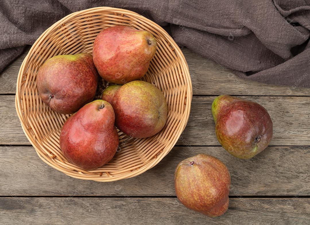 Peras vermelhas em uma tigela sobre a mesa de madeira.