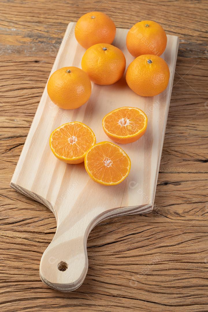Mini tangerinas em uma placa sobre a mesa de madeira.