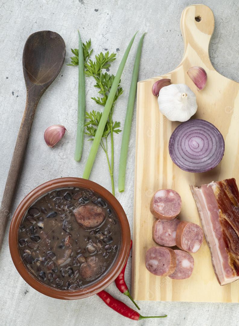 Brazilian traditional feijoada in a bowl with ingredients