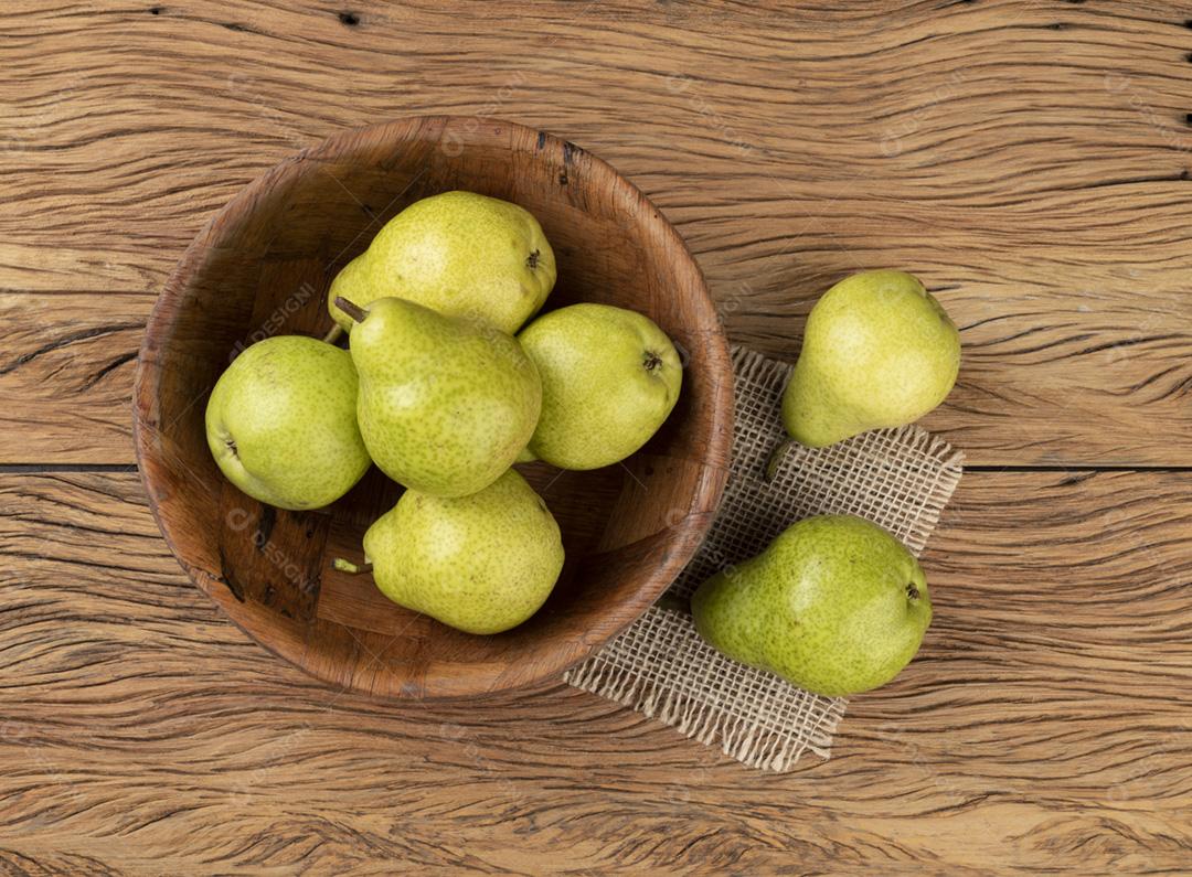 Peras verdes em uma tigela sobre a mesa de madeira