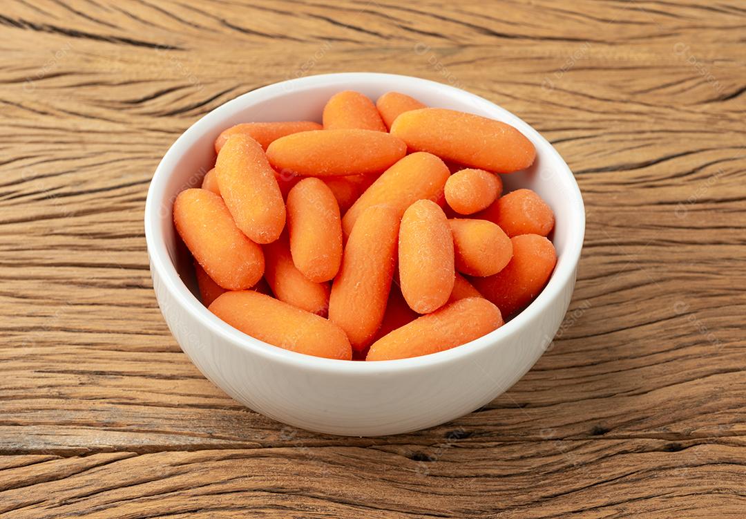 Cenouras em uma tigela sobre a mesa de madeira.