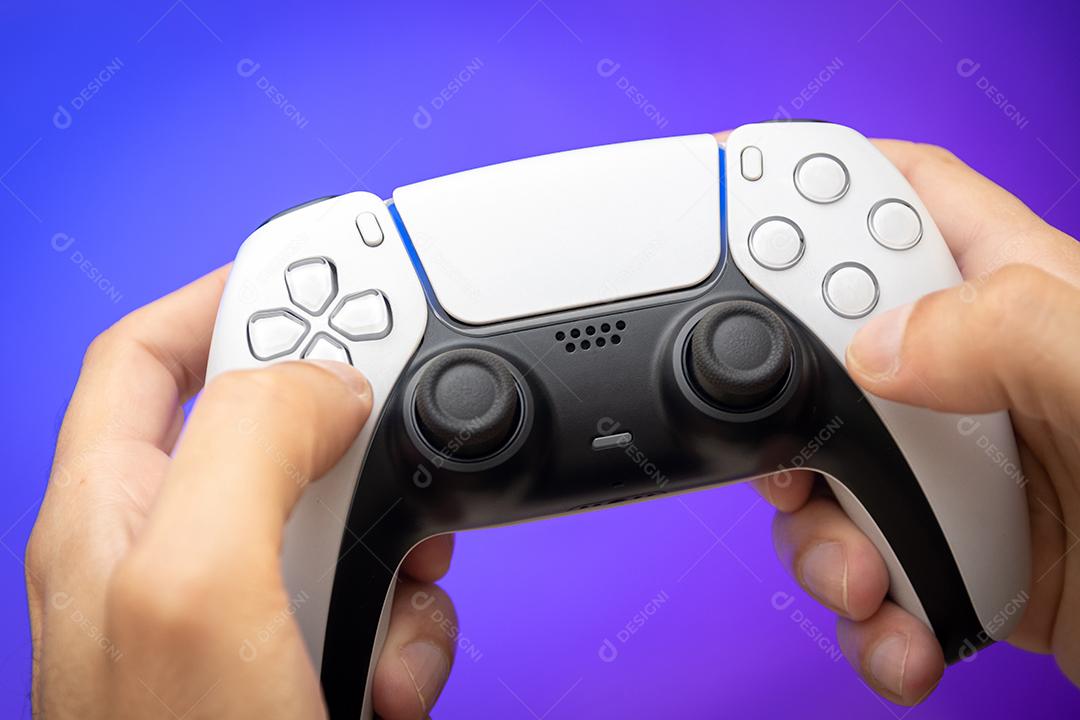 Controlador de jogo nas mãos do homem com fundo roxo.