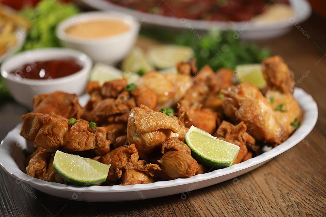 Porção de frango frito com limão. Alface, cebolinha, ketchup e maionese.