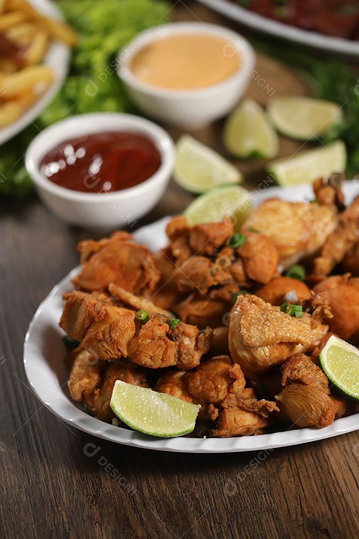 Porção de frango frito com limão. Alface, cebolinha, ketchup e maionese.