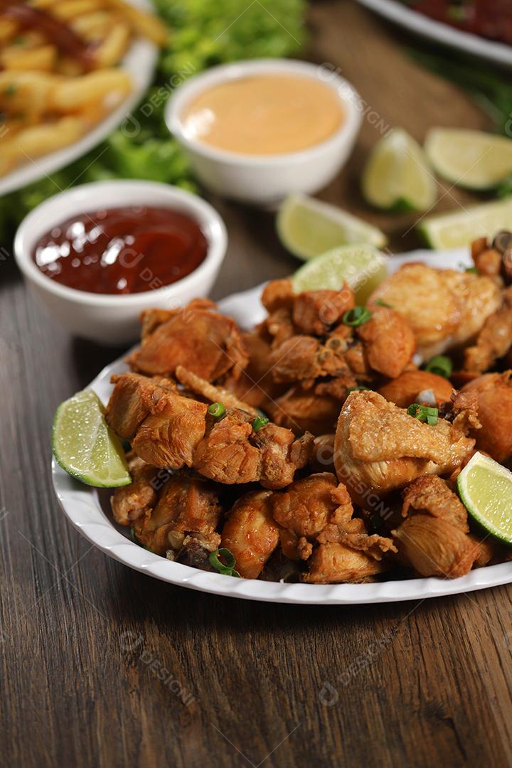 Porção de frango frito com limão. Alface, cebolinha, ketchup e maionese.