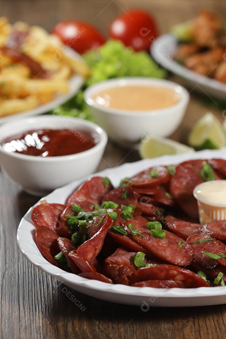 Porção de linguiça calabresa com limão. Alface, cebolinha, ketchup e maionese.