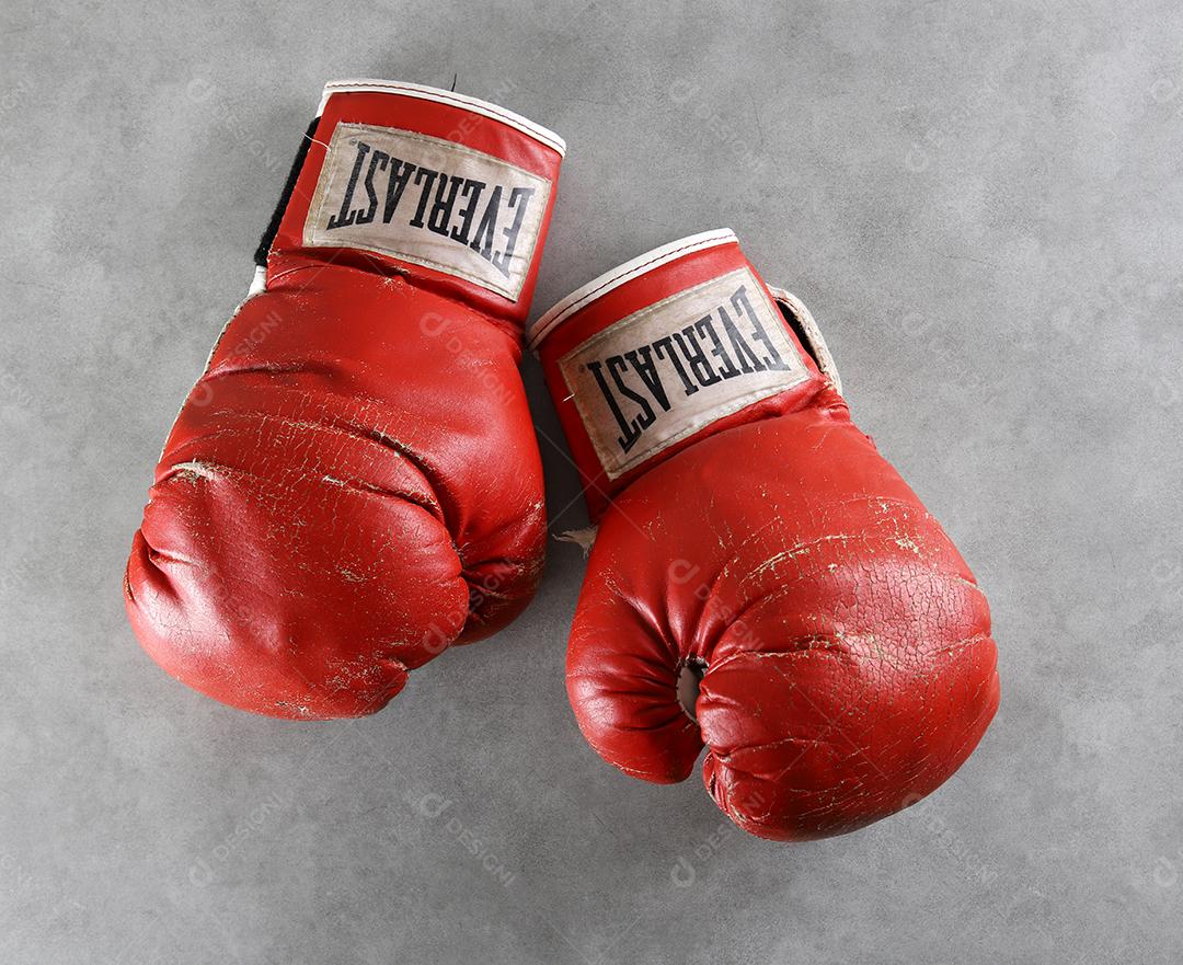 Luvas de boxe velhas Eternas no chão do ginásio após o treino. Fundo cinza concreto grunge.