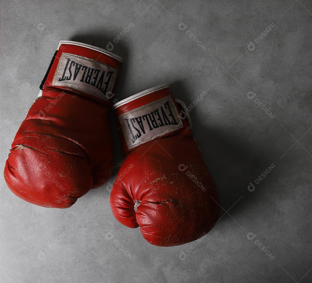 Luvas de boxe velhas Eternas no chão do ginásio após o treino. Fundo cinza concreto grunge.