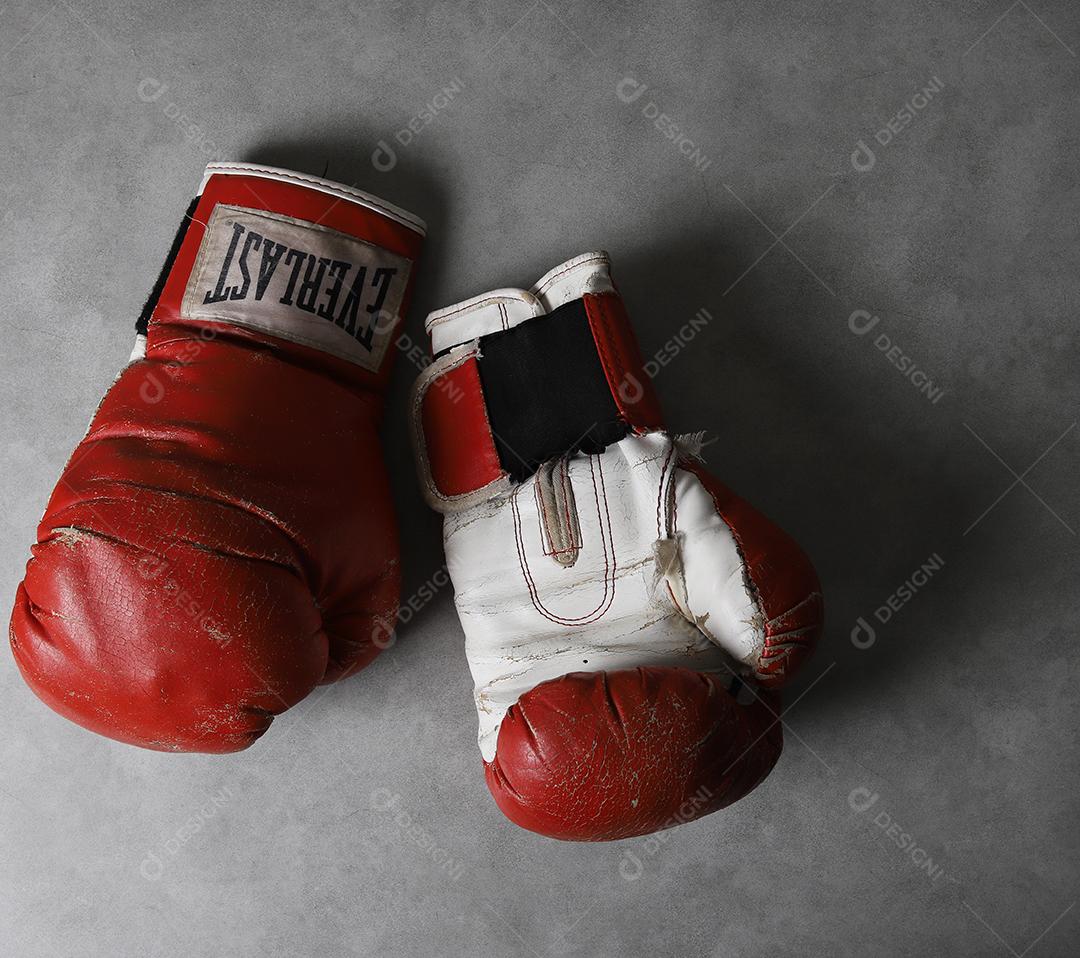 Luvas de boxe velhas Eternas no chão do ginásio após o treino. Fundo cinza concreto grunge.