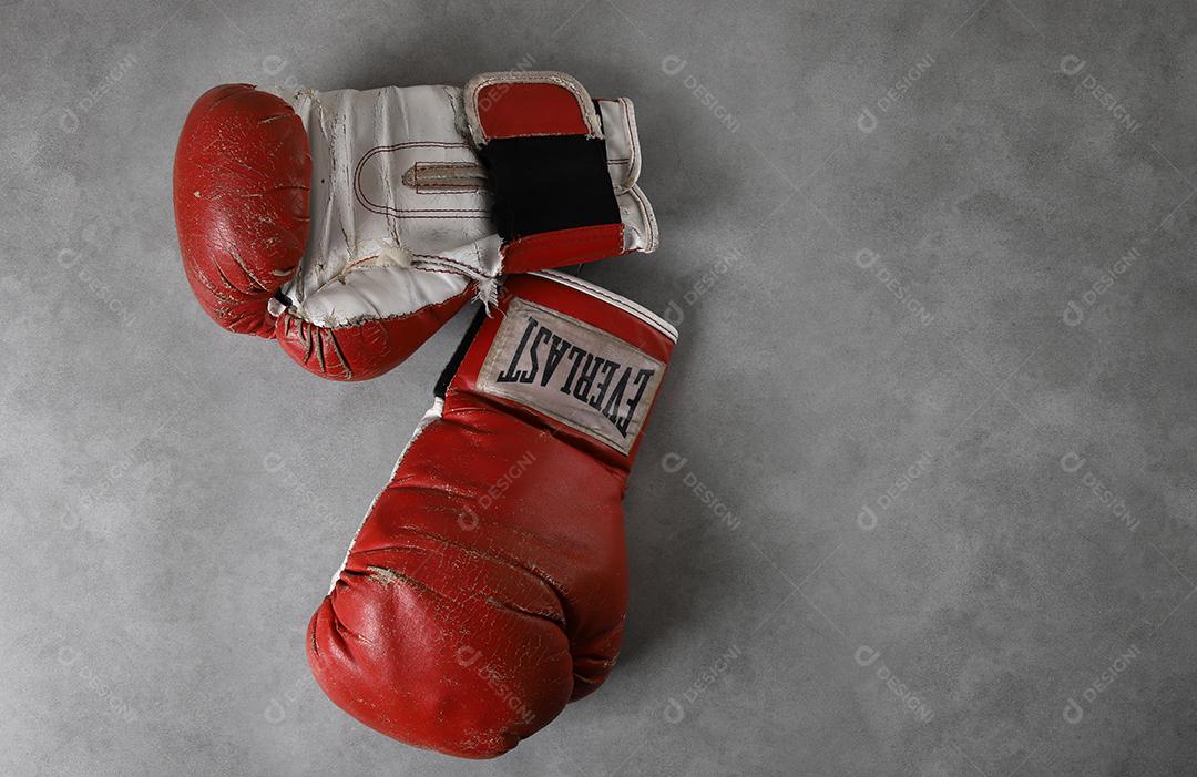 Luvas de boxe velhas Eternas no chão do ginásio após o treino. Fundo cinza concreto grunge.