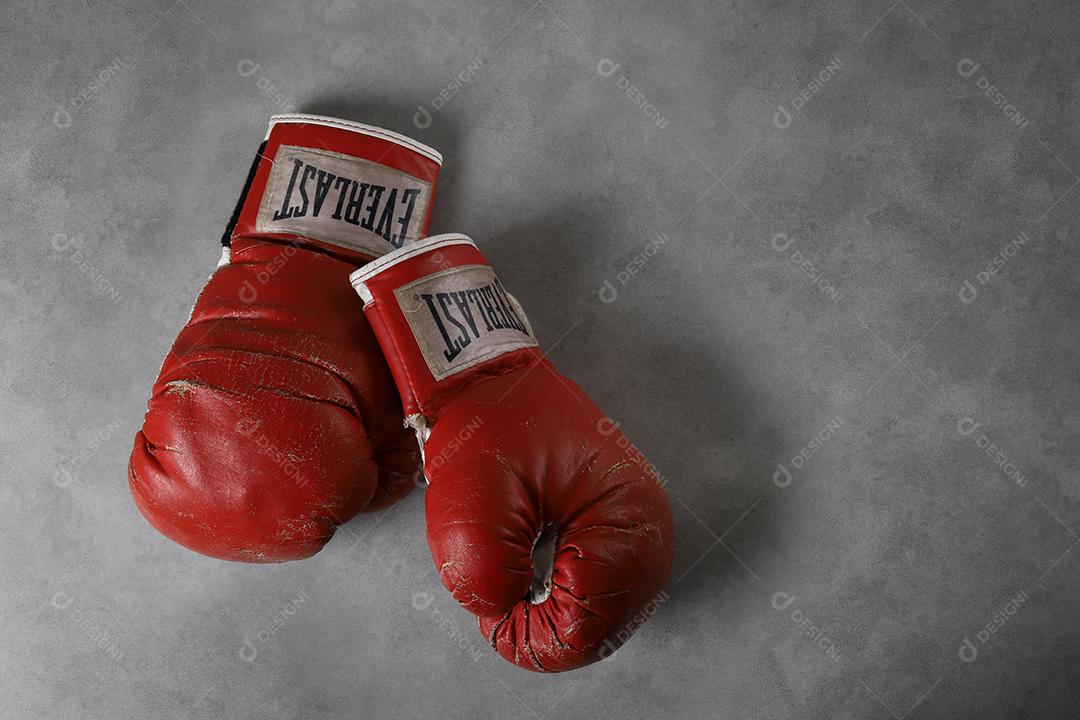 Luvas de boxe velhas Eternas no chão do ginásio após o treino. Fundo cinza concreto grunge.