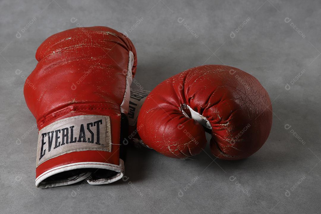 Luvas de boxe velhas Eternas no chão do ginásio após o treino. Fundo cinza concreto grunge.