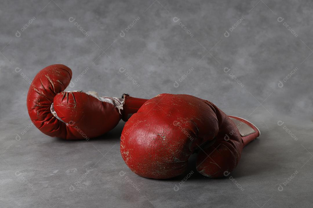 Luvas de boxe no chão do ginásio após o treino. Fundo de concreto cinza grunge.