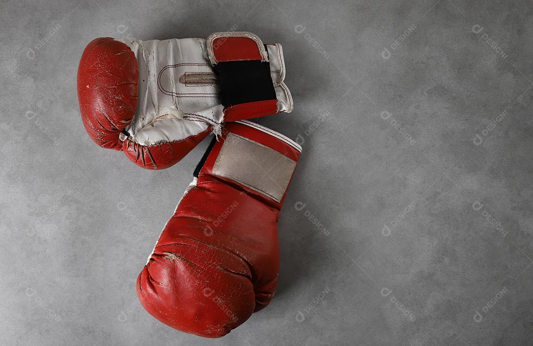 Luvas de boxe no chão do ginásio após o treino. Fundo de concreto cinza grunge.