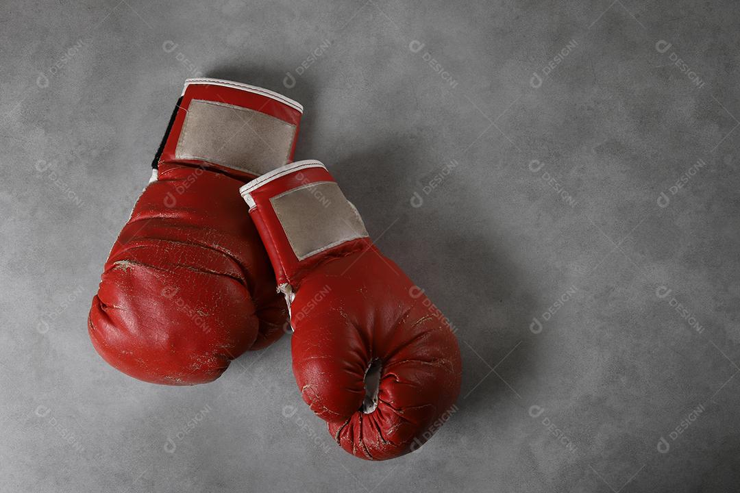 Luvas de boxe no chão do ginásio após o treino. Fundo de concreto cinza grunge.