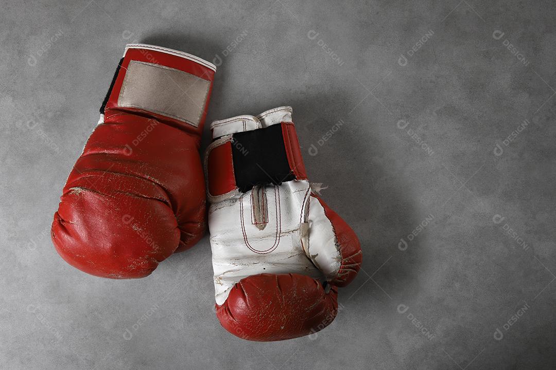 Luvas de boxe no chão do ginásio após o treino. Fundo de concreto cinza grunge.
