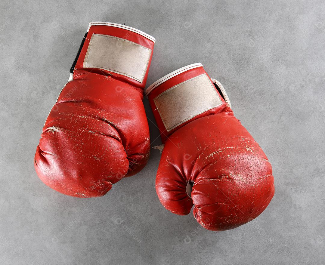 Luvas de boxe no chão do ginásio após o treino. Fundo de concreto cinza grunge.