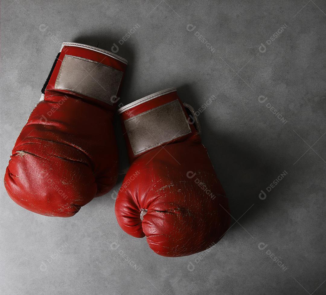 Luvas de boxe no chão do ginásio após o treino. Fundo de concreto cinza grunge.