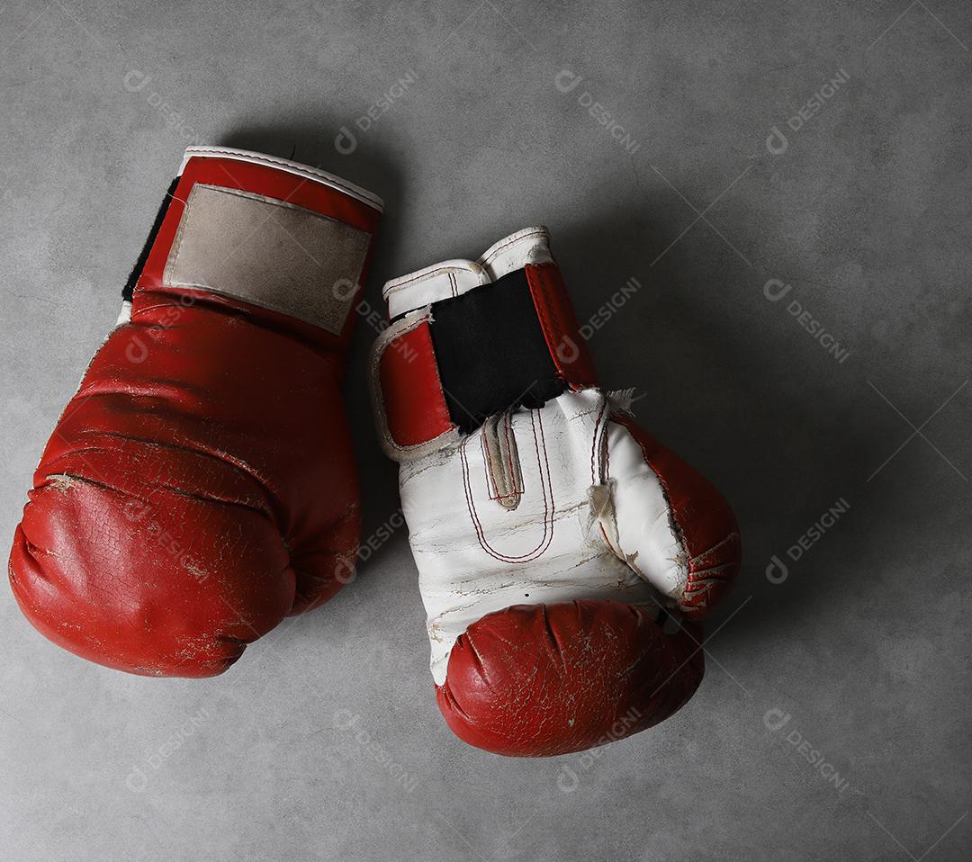 Luvas de boxe no chão do ginásio após o treino. Fundo de concreto cinza grunge.