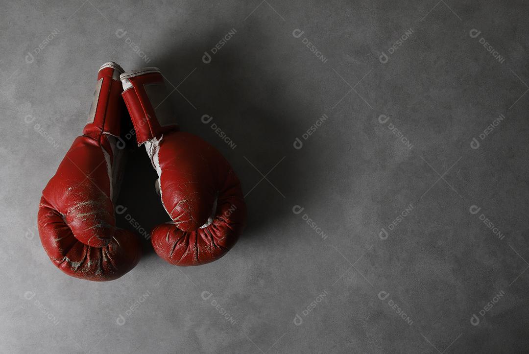 Luvas de boxe no chão do ginásio após o treino. Fundo de concreto cinza grunge.