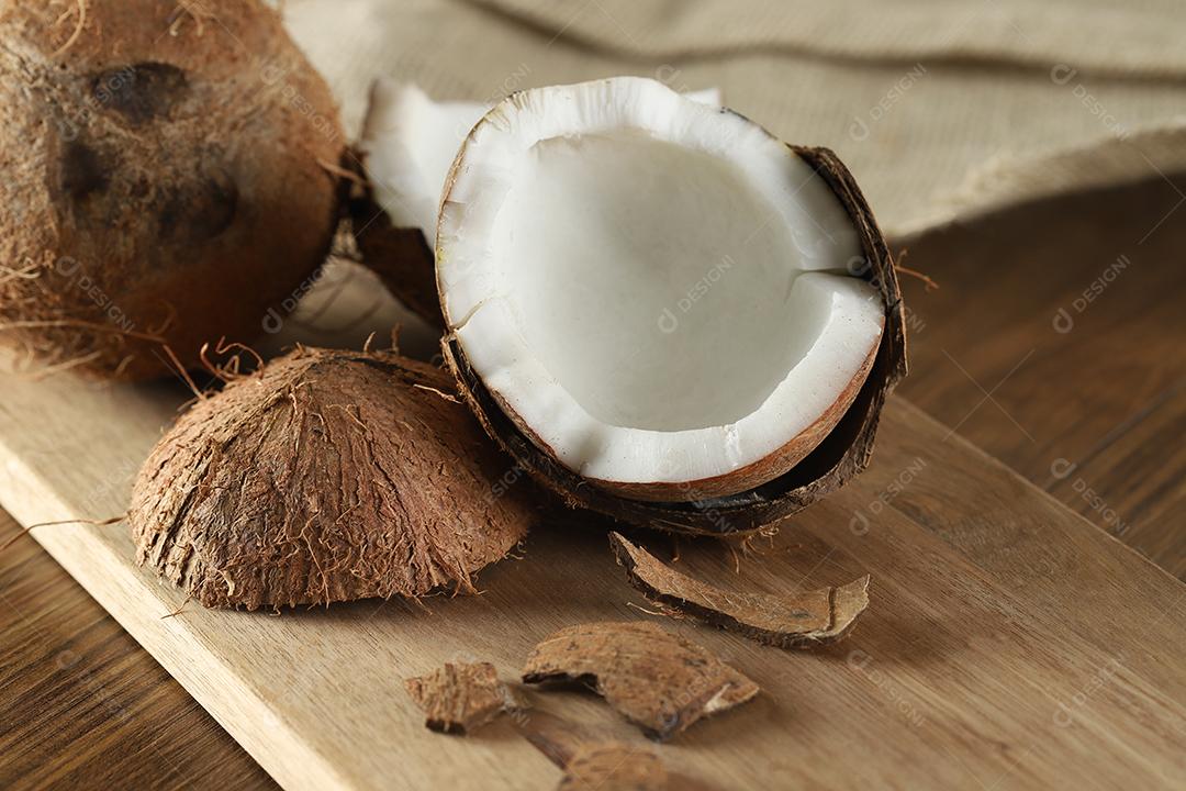 Meio coco maduro cortado em um fundo de madeira. Coco maduro cortado ao meio em um fundo de madeira.