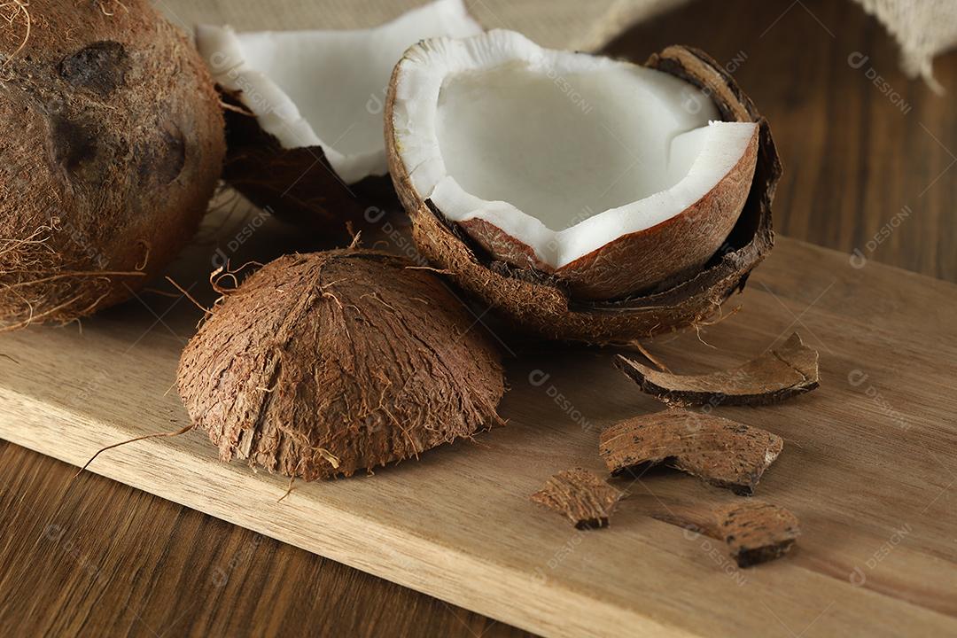 Meio coco maduro cortado em um fundo de madeira. Coco maduro cortado ao meio em um fundo de madeira.