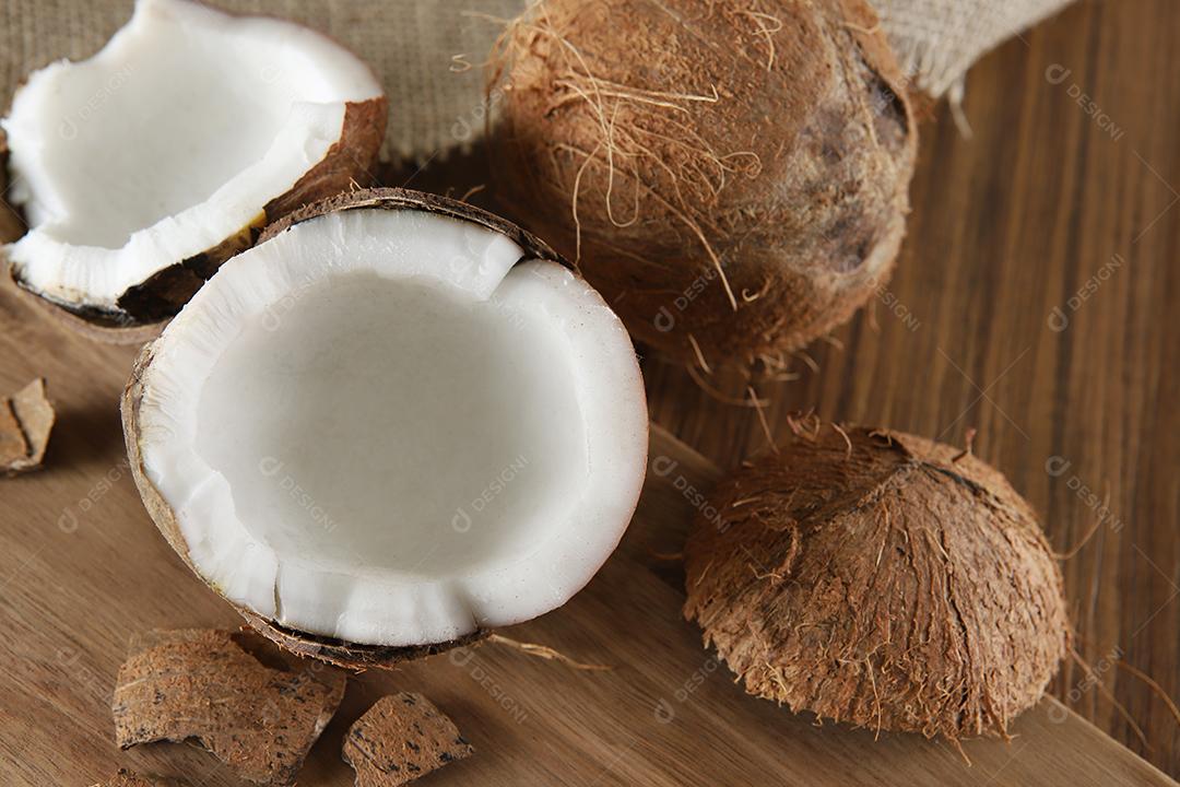 Meio coco maduro cortado em um fundo de madeira. Coco maduro cortado ao meio em um fundo de madeira.
