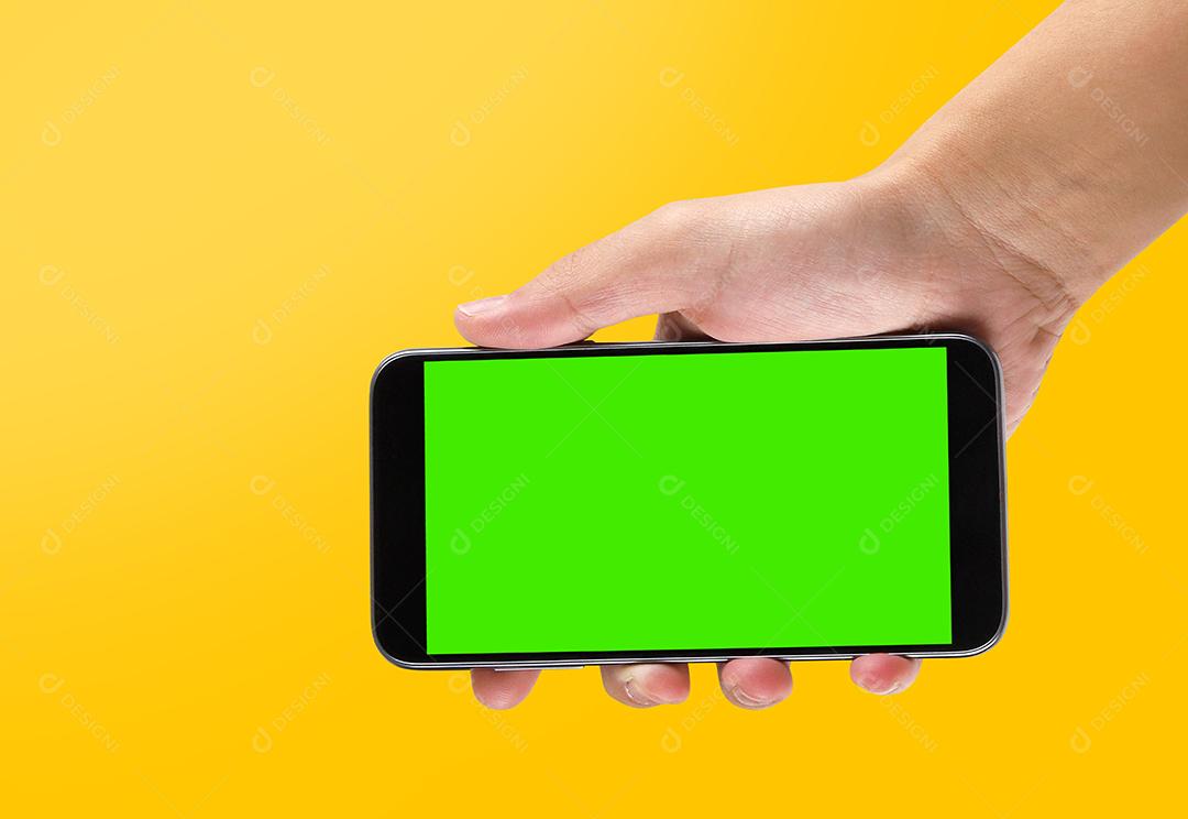 Mão segurando o celular na tela de fundo amarelo e croma.