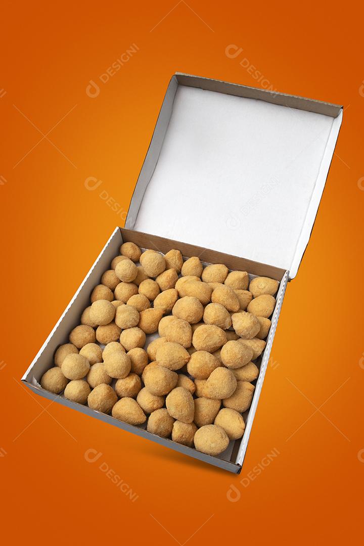 Uma caixa de croquetes fritos e aperitivos para entrega. Coxinha de lanche brasileiro em fundo amarelo e laranja.