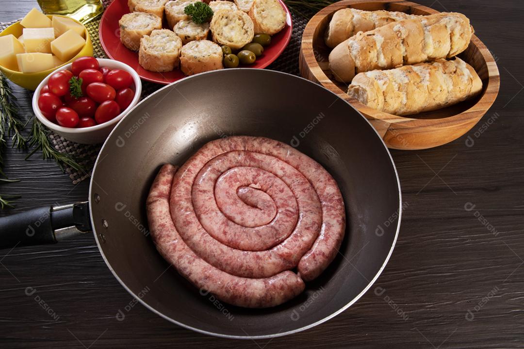 Linguiça assada com pão de salsicha e alho em um prato vermelho na mesa de churrasco wi