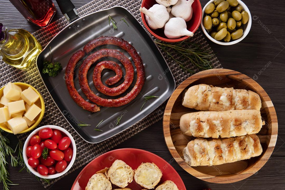 Linguiça assada com pão de salsicha e alho em um prato vermelho na mesa de churrasco wi
