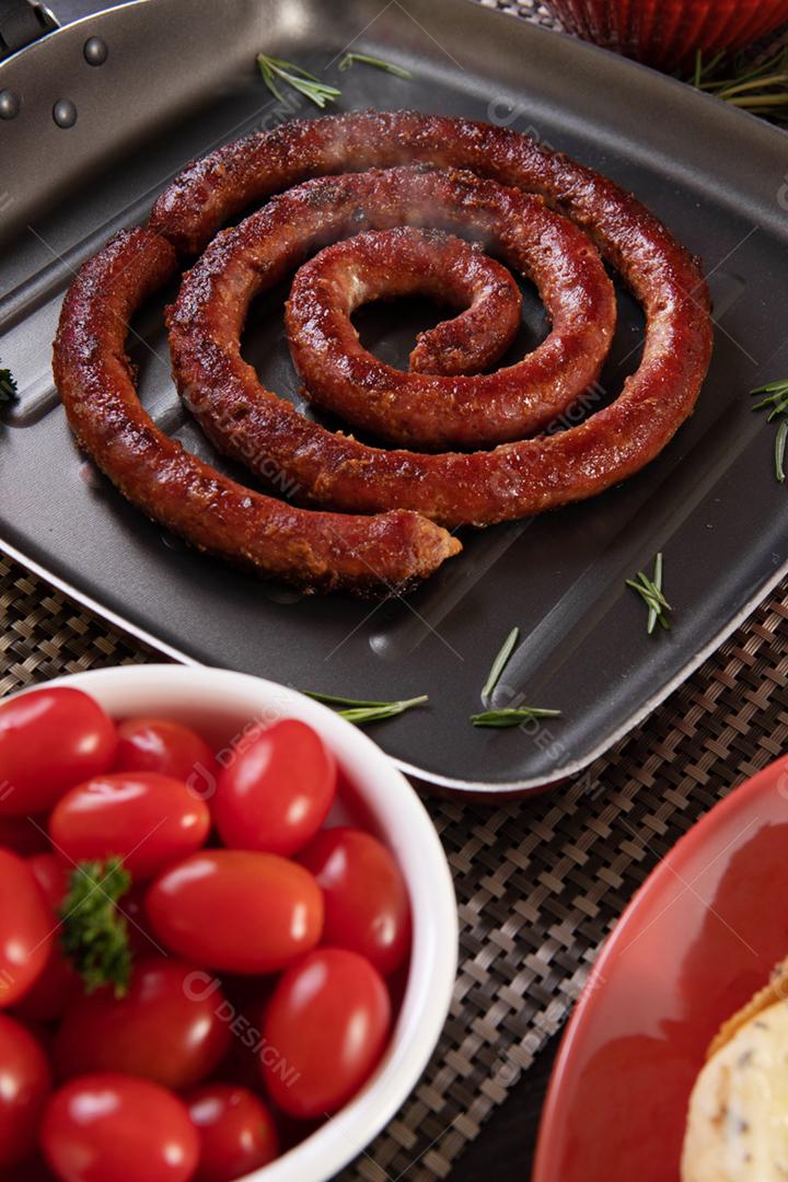 Pão de salsicha e alho em um prato vermelho na mesa de churrasco wi